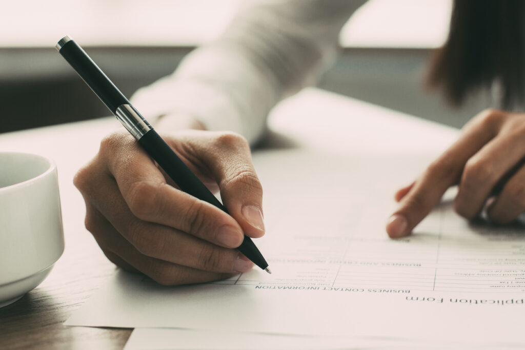 Woman writing a cover letter and filling a job application form at home