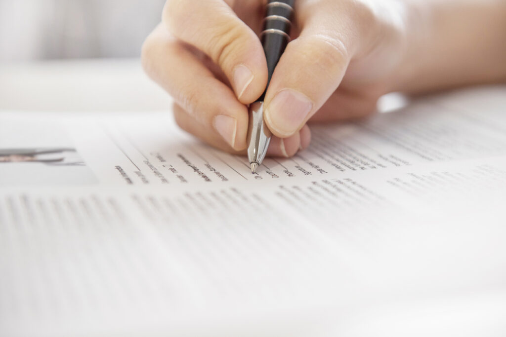 mano que sostiene un bolígrafo escribiendo palabras para describirse en el currículum